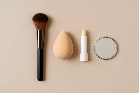 Flat lay : pinceau, éponge humidifiée, baume et petit miroir sur fond beige — maquillage discret Tintiva.